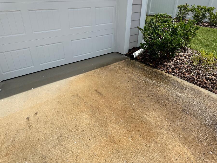 Concrete driveway pressure washing before, darkened by mildew and traffic film, Windermere FL