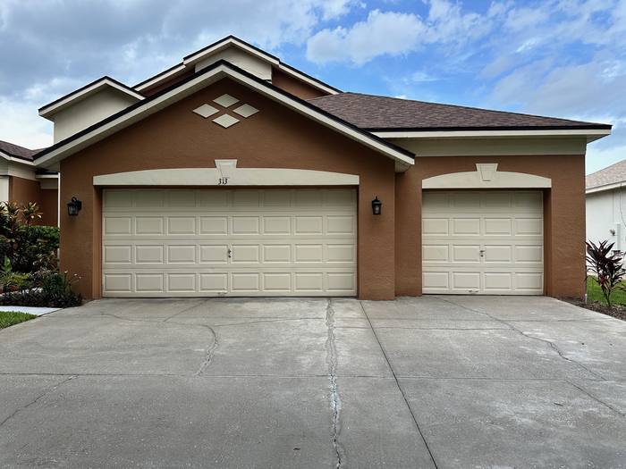 Concrete driveway after pressure washing at a three-car garage, uniform clean finish up to the garage doors, Central Florida