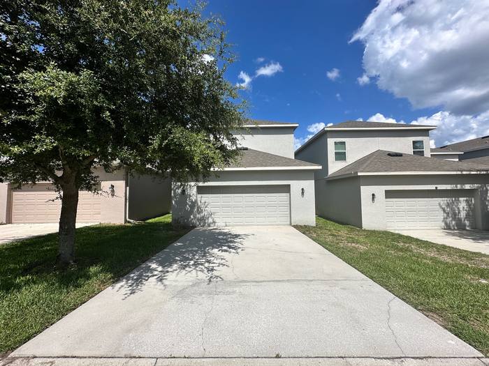 Concrete driveway after pressure washing in front of a two-story stucco home, bright and evenly cleaned, Central Florida
